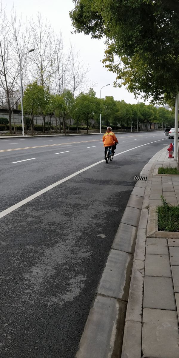 广电江湾小区附近,空旷的路面上一位骑行的环卫工人(记者 吴小飞/摄)